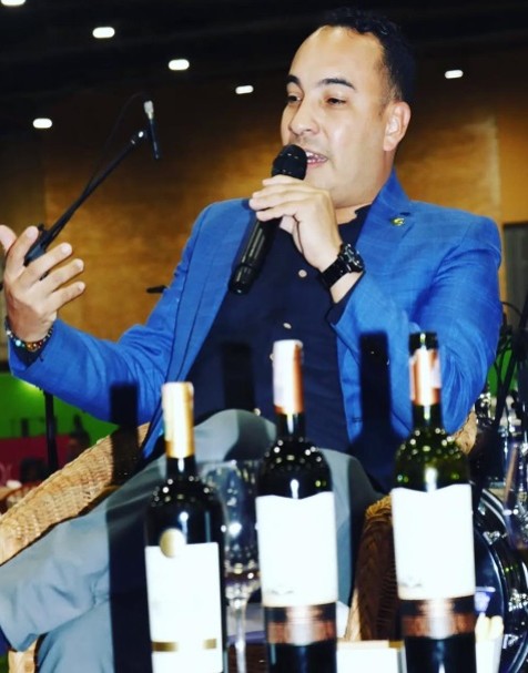 Sommelier de Stage guiando una cata de vinos con micrófono frente a botellas